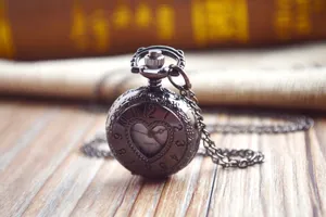 Detailshot van een antiek bronzen zakhorloge met holle hart wijzerplaat en bijpassende ketting.