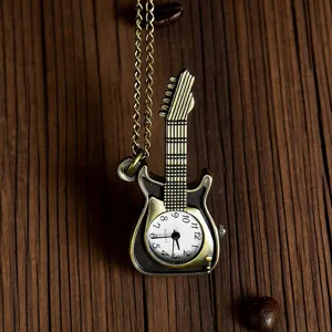 Close-up view of vintage bronze guitar pocket watch pendant with delicate chain on wooden surface.