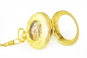 Detailed shot of vintage gold skeleton pocket watch with engraved floral cover and chain.