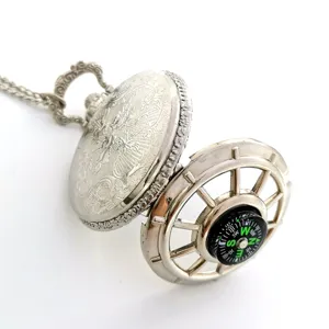Vintage silver pocket watch with internal compass, ornate engraved case, and chain necklace detail shot.