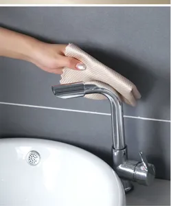 Detailed view of microfiber fish scale cleaning cloth wiping faucet in bathroom, highly absorbent.