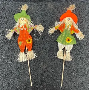 Primo piano dettaglio di picchetti da giardino spaventapasseri autunnali con cappelli di paglia.