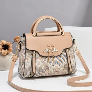 Chic women's top handle shoulder bag with brocade fabric, elegant swan clasp and leather trim.