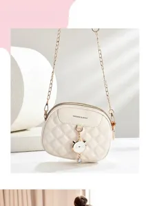 Detailansicht einer eleganten cremefarbenen Stepptasche mit goldener Kette und Anhänger
