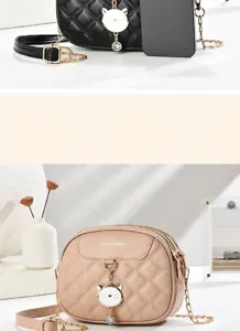 Elegante gesteppte Umhängetasche mit Katzenanhänger in Schwarz und Beige.