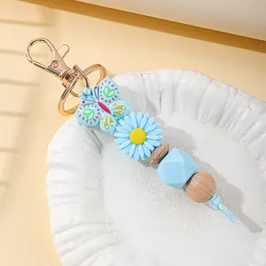 Close-up detail of soft silicone butterfly and blue daisy beads on a handmade keychain