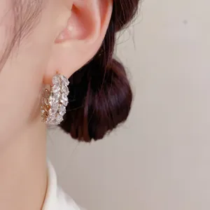 Close-up detail of elegant cubic zirconia wheat hoop earrings on a female model ear