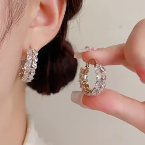 Detailed view of elegant zircon wheat ear hoop earrings worn and held in close-up shot