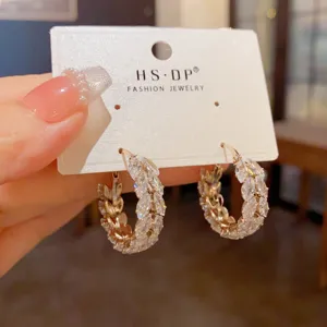 Close-up of elegant zircon hoop earrings with wheat ear design on a jewelry card