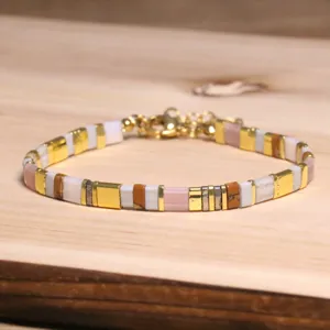Gros plan sur les perles Tila colorées et les accents dorés du bracelet tissé
