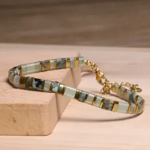 Détail macro du bracelet de perles Tila fait main avec des touches de vert et d'or.