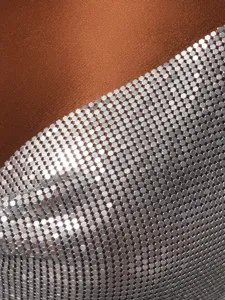 Macro detail of shimmering silver metallic mesh sequins on a brown fabric top.