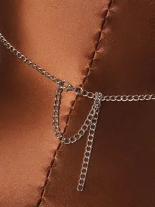 Close-up detail of the adjustable silver-tone metal chain closure on a brown satin garment.