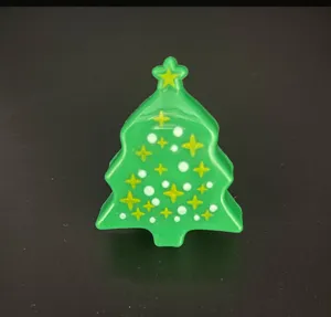 Closeup detail of Christmas tree shaped glowing toy ring with star patterns and white dots.