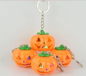 Halloween pumpkin keychain detail shot, glowing LED lights inside plastic pumpkin pendant.