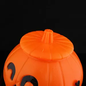 Halloween plastic pumpkin candy bucket with lid, orange jack-o-lantern prop for party decor.