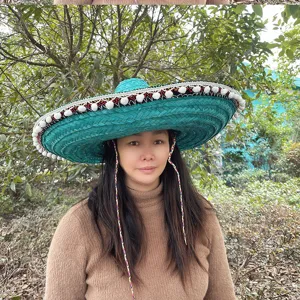 Green Mexican straw hat with white pom poms and colorful braided straps, ideal for party wear.