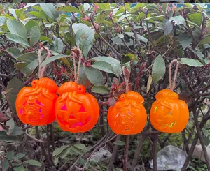 Outdoor hanging pumpkin lights detail shot, plastic material with glowing effect and twine rope.