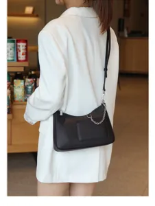 Leather underarm bag for women, black crescent shoulder bag with chain strap and front pocket details.