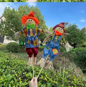 Handmade scarecrow doll decoration for autumn garden, standing straw figures with plaid shirt.