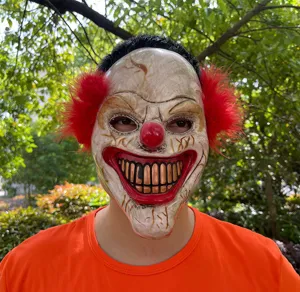 Close-up detail of scary clown mask with red hair, creepy smile and realistic texture for party.