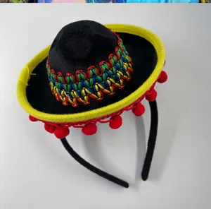 Detailed view of miniature Mexican fiesta hat headband with colorful woven pattern and red pom poms.