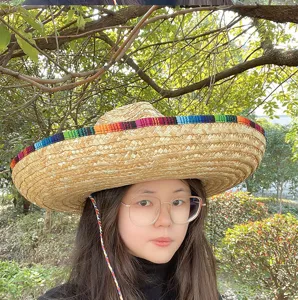 Detailed view of a Mexican straw hat with colorful woven band and chin cord worn outdoors.