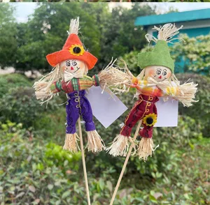 Close up of cute Halloween scarecrow garden stake with straw hair and colorful outfit for party decor.