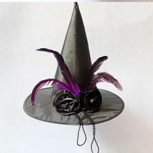 Primo piano del cappello da strega nero con piume viola, rose di stoffa e perline.