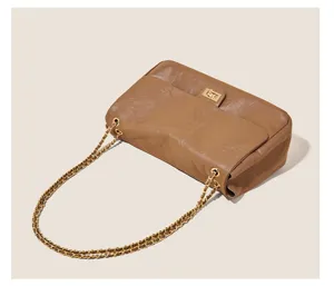 Detailed view of brown quilted leather shoulder bag with gold chain strap and metal lock.