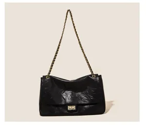 Black leather shoulder bag detail, vintage crinkled texture, gold chain and metal lock