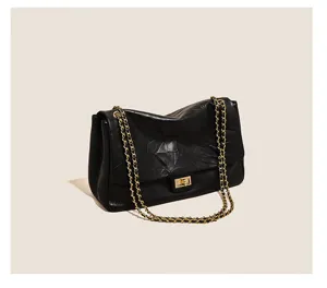 Black leather shoulder bag detail, quilted design with gold chain strap and turn-lock.