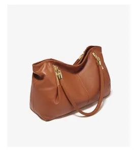 Brown leather shoulder bag detail showing premium texture and gold hardware accents.