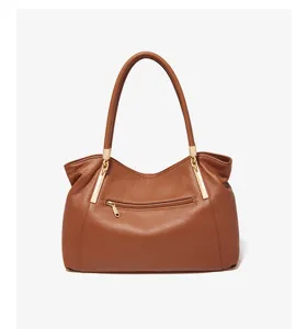 Brown leather shoulder bag detail showing premium texture, golden hardware and secure zipper pocket.