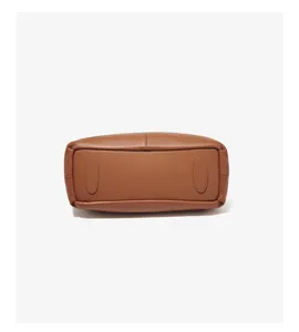 Detailed view of brown leather crossbody bag bottom with protective feet, premium texture.