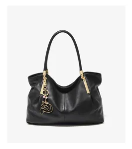 Close-up of black leather shoulder bag featuring textured fabric and elegant golden fox charm.