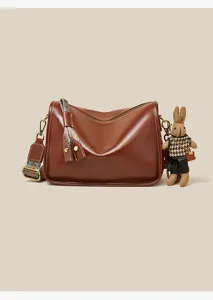 Retro brown leather shoulder bag detail with chic rabbit pendant and ethnic strap design.
