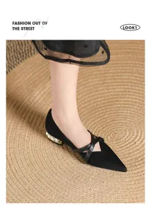Gros plan sur des chaussures plates noires à bout pointu, talon perlé et brides croisées.