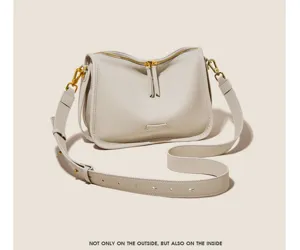 Detail view of minimalist soft leather crossbody bag with gold hardware and wide strap.
