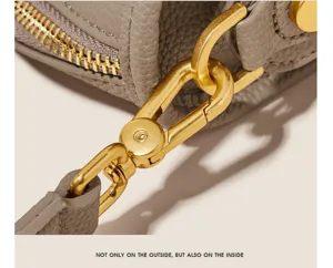 Close-up detail shot of grey leather handbag gold metal hardware zipper and clasp accessory.