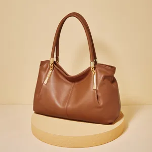 Brown leather shoulder bag for women, elegant tote handbag with gold-tone hardware on podium.