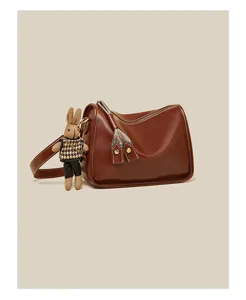Detailed view of retro brown leather shoulder bag with cute rabbit plush toy charm.
