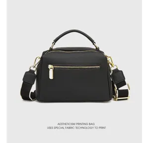 Detailed view of black genuine leather handbag with gold metal hardware, zipper and strap.