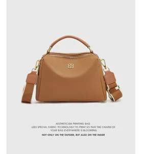 Stylish brown genuine leather boston handbag for women with top handle and wide strap.