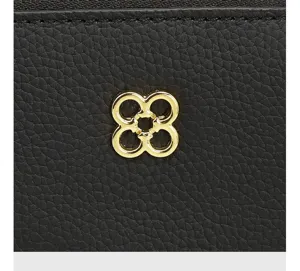 Black genuine leather handbag detail featuring a luxury gold flower metal logo hardware.