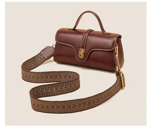 Vintage brown leather crossbody bag with top handle, wide patterned strap, and metal lock.