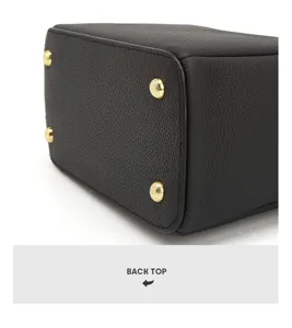 Genuine leather handbag bottom detail shot showcasing durable cowhide and sleek gold metal feet.