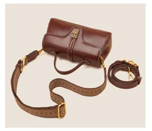 Brown genuine leather top-handle handbag with patterned wide shoulder strap and extra strap.