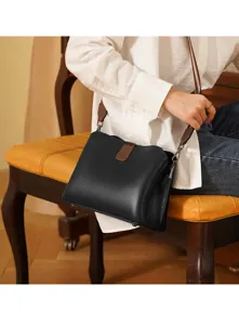 Primo piano dell'elegante borsa a tracolla in pelle nera con dettagli di cinturino marrone.