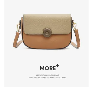 Detailed view of genuine leather two-tone saddle crossbody bag with chic circular clasp.